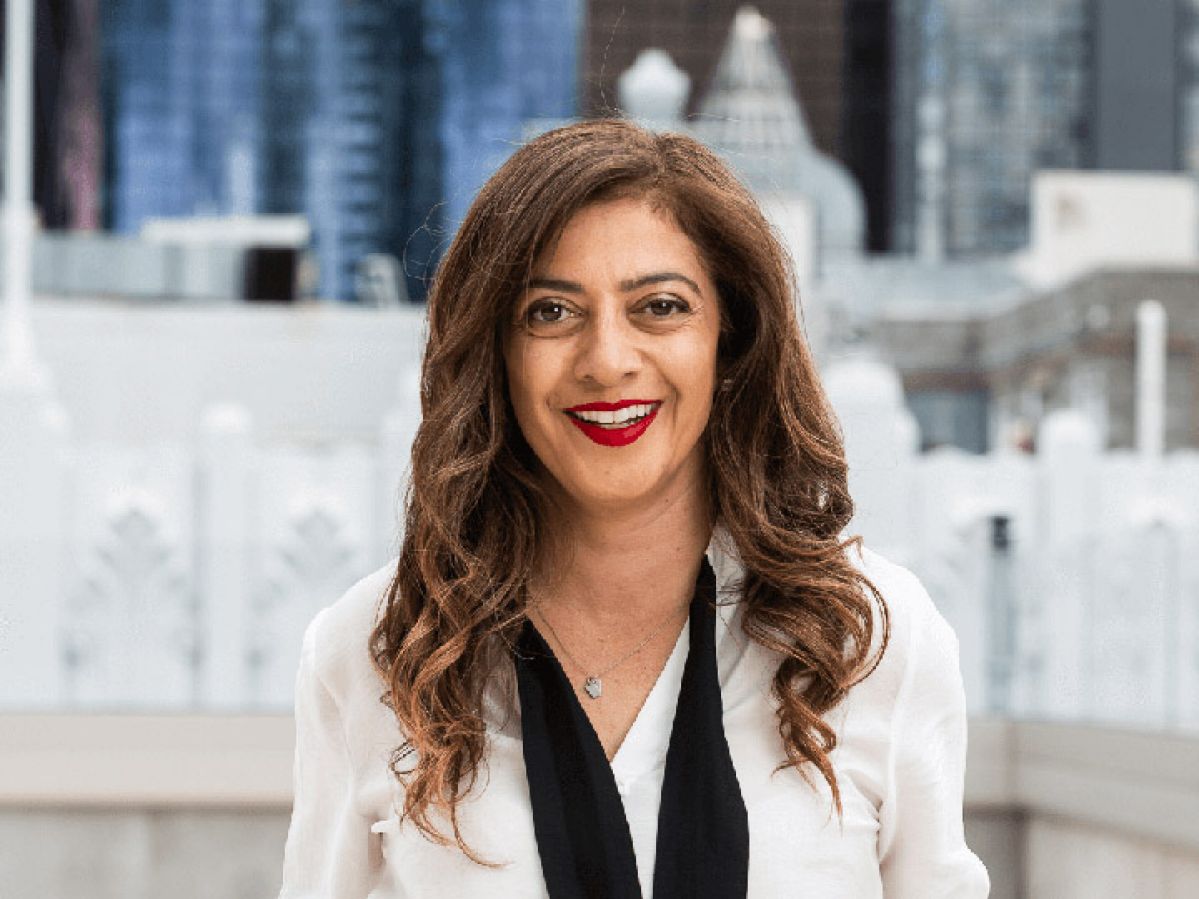 Woman in business clothes smiling on a building's balcony in the city.