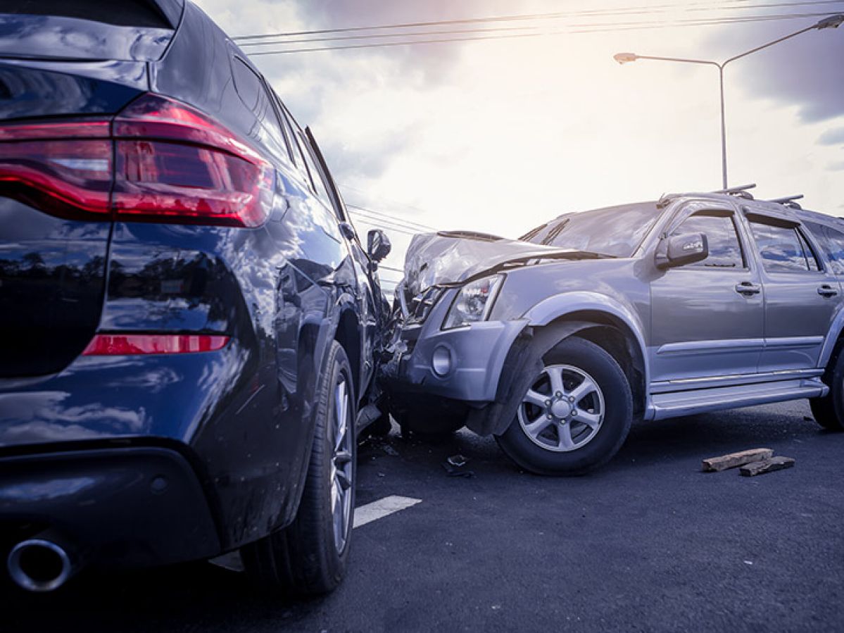 Side-on collision of a silver and navy car. The front of the silver car is crumpled.