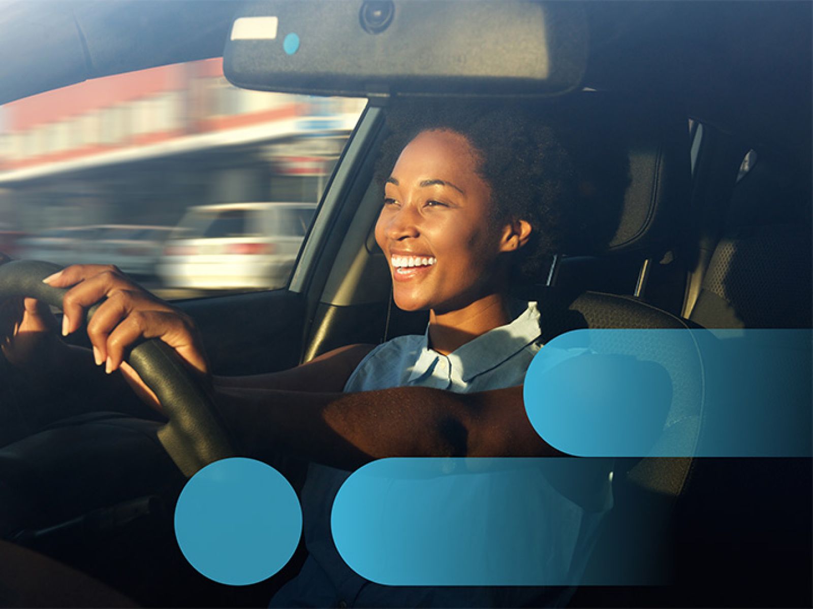 A person in business clothes, smiling while driving out of a car park.
