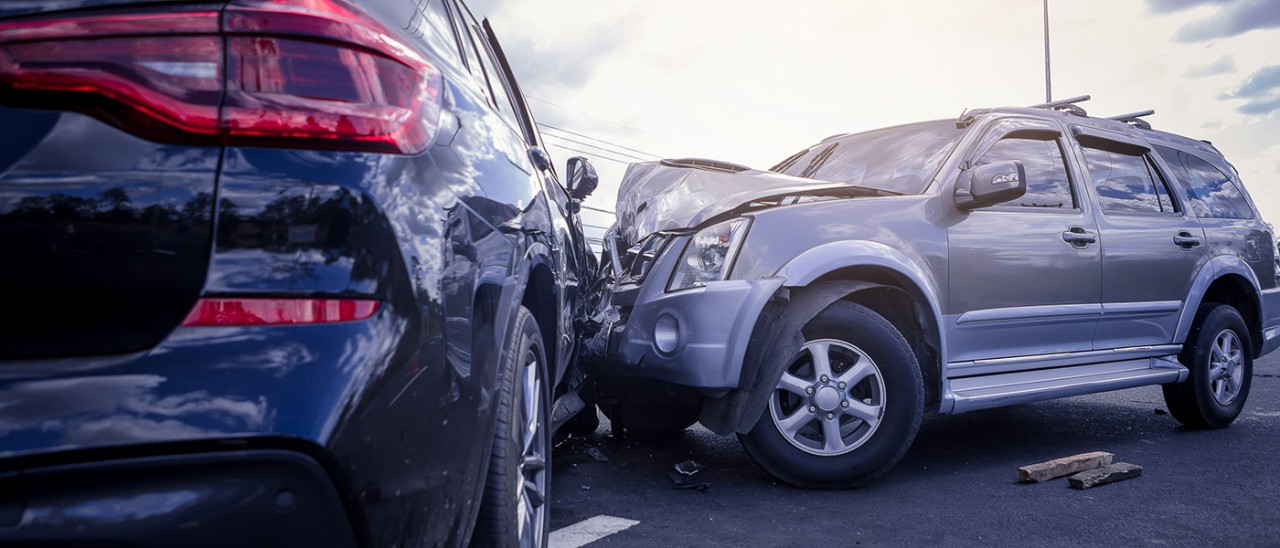 Side-on collision of a silver and navy car. The front of the silver car is crumpled.