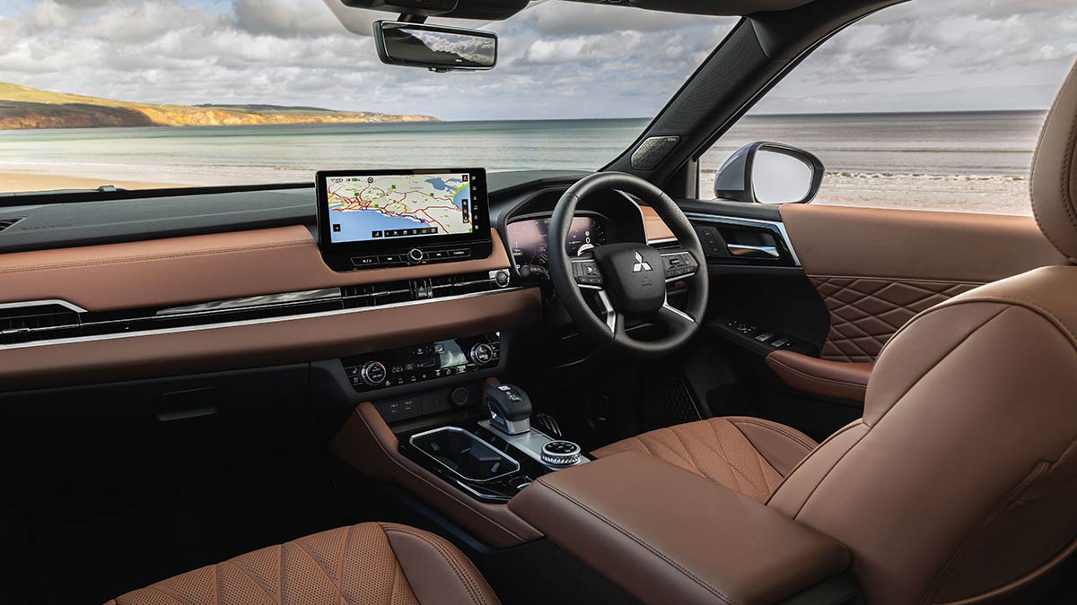 The front seats of a Mitsubishi Outlander, showing brown leather seats and a central touchscreen.